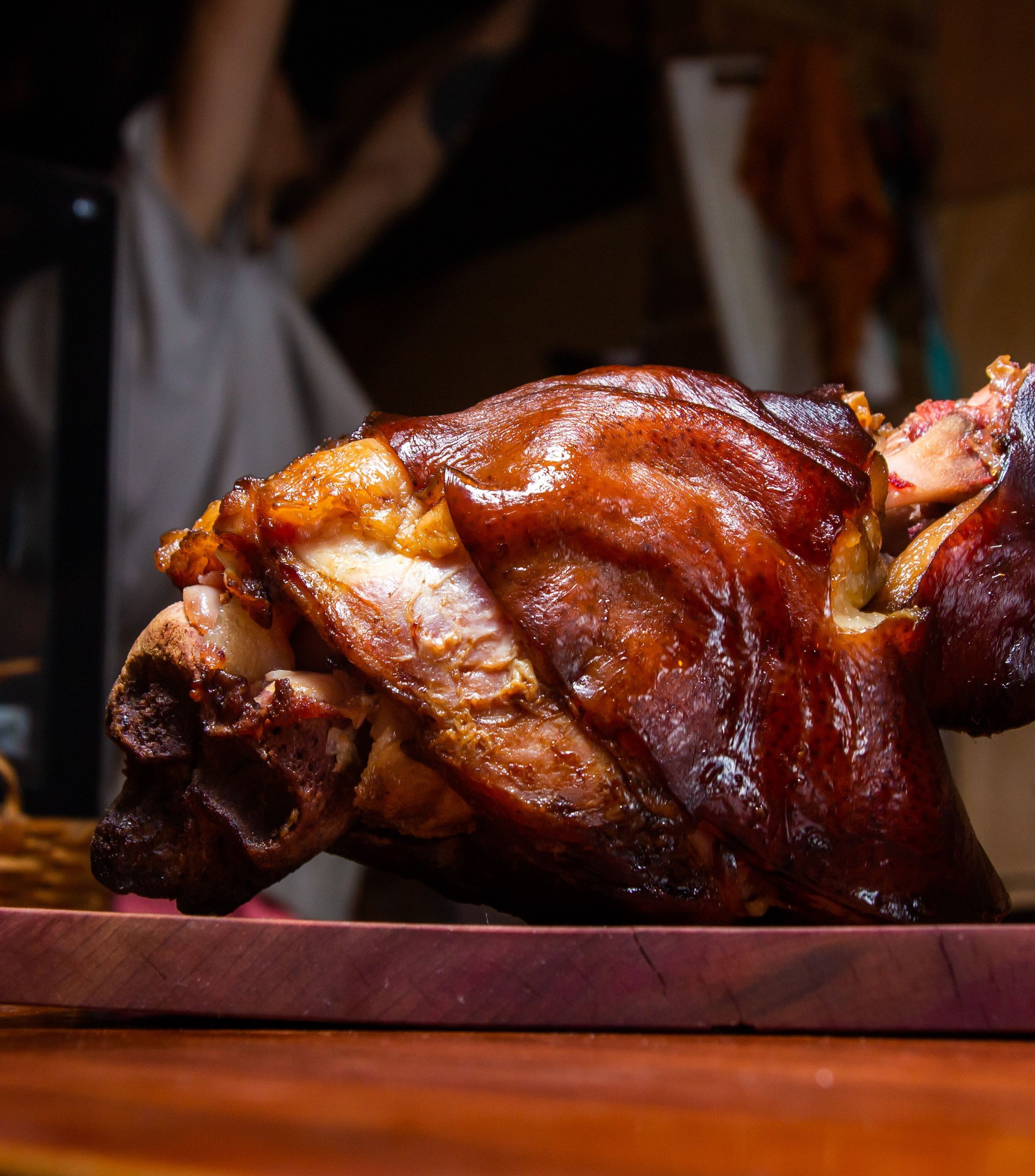 Illustrative stock photograph of a crisp-skinned pork knuckle on a board; restaurant presentation differs